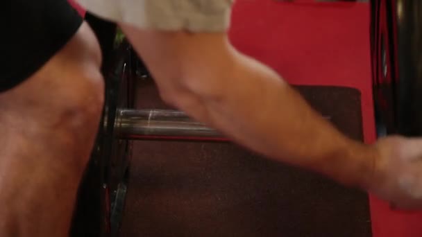 Handsome athletic man puts weight on a barbell in the gym. — Stock Video