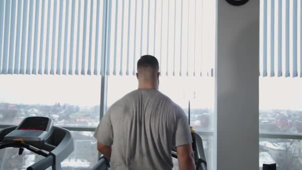 Bel homme athlétique exerçant sur le tapis roulant dans la salle de gym . — Video