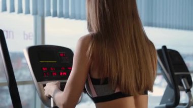 Eliptik bir eğitmen salonunda güzel atletik genç kız trende