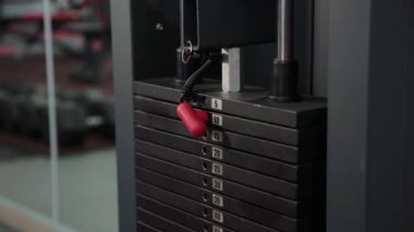 Simülatör ağırlığıyla bar değiştirmek bir kızın yakın çekim. Vücut geliştirme. Simülatör üzerinde ağırlığı spor salonunda, ayarlar için kız gider.