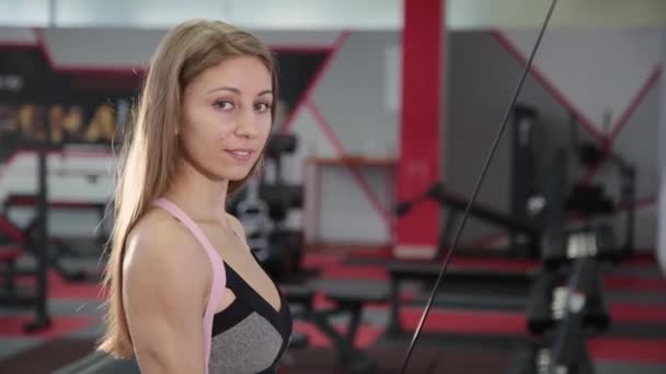 Η κοπέλα την επέκταση των βραχιόνων εκτελεί για τα triceps σε προσοµοιωτή μπλοκ. — Αρχείο Βίντεο