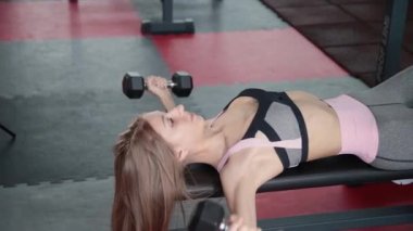 Güzel atletik genç kız halter salonunda göğüs kasları egzersizleri.