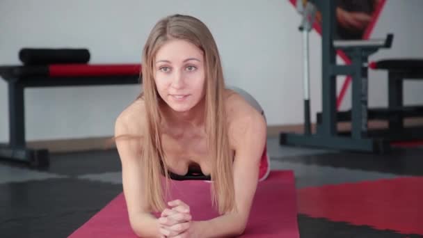 Giovane donna che fa esercizio plancia in palestra. Ragazza ceppi muscoli della pressa addominale . — Video Stock