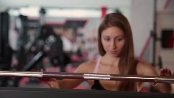 Belle jeune fille athlétique venant au bar pour squats dans la salle de gym . — Video