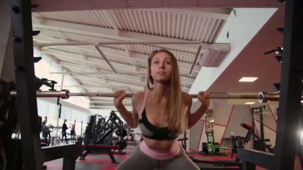 Hermosa chica atlética se agacha en los hombros en el gimnasio . — Vídeos de Stock