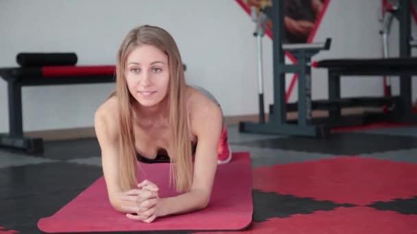 Jonge vrouw doen oefening plank in de sportschool. Meisje stammen spieren van buik pers. — Stockvideo