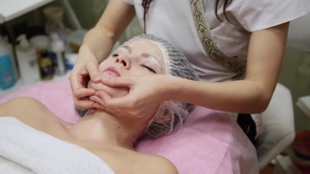 Spa mujer masaje facial. Masaje facial en salón de spa de belleza. Mujer disfrutando de masajes faciales relajantes en el centro de spa de cosmetología. Cuidado corporal, cuidado de la piel, bienestar, tratamiento de belleza . — Vídeos de Stock