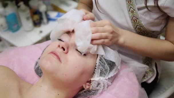Menina muito bonita limpa o rosto com guardanapos antes de massagear o rosto no salão de spa . — Vídeo de Stock