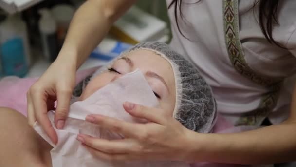 Very beautiful girl wipes her face with napkins before massaging her face in the spa salon. — Stock Video