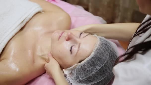 Спа жінка масаж обличчя. Обличчя Масаж в салоні краси. Жінка насолоджується розслабляючим масажем обличчя в косметологічному спа-центрі. Догляд за тілом, догляд за шкірою, оздоровлення, лікування краси . — стокове відео