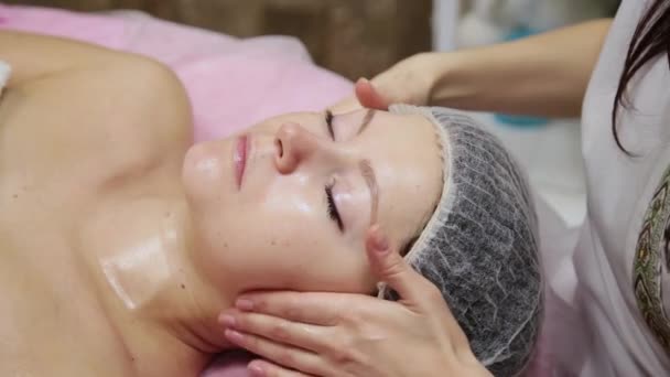 Spa mulher facial Massagem. Massagem facial no salão de beleza spa. Feminino desfrutando de relaxante massagem facial no centro de spa cosmetologia. Cuidados com o corpo, cuidados com a pele, bem-estar, tratamento de beleza . — Vídeo de Stock