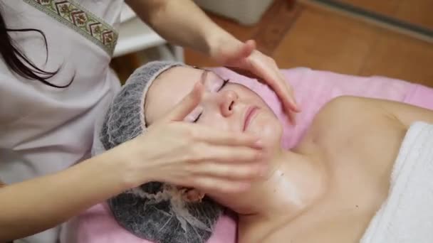 Spa mujer masaje facial. Masaje facial en salón de spa de belleza. Mujer disfrutando de masajes faciales relajantes en el centro de spa de cosmetología. Cuidado corporal, cuidado de la piel, bienestar, tratamiento de belleza . — Vídeos de Stock