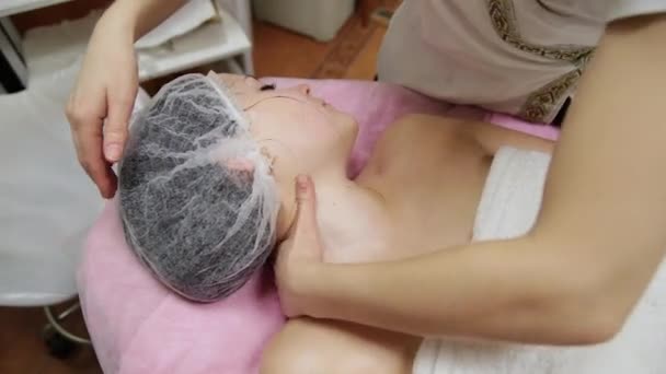 Aantrekkelijke vrouw in spa healthclub krijgen een gezichtsmassage. Schoonheidsspecialiste doen massage van het gezicht, nek en schouders van beautyful jonge vrouw op luxe beauty salon — Stockvideo