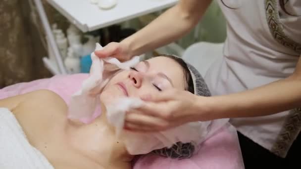 Chica muy hermosa se limpia la cara con servilletas antes de masajear su cara en el salón de spa . — Vídeo de stock