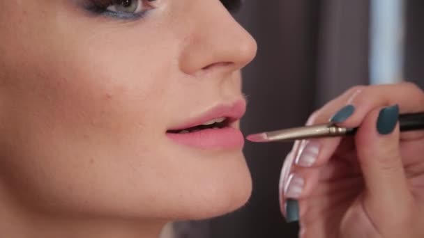 Truccatore utilizzando pennello per l'applicazione rossetto sulle labbra bella donna. Luminosità di labbro di applicazione vicina su modello di moda di labbra. Visagiste che si trucca le labbra. Concetto bellezza . — Video Stock