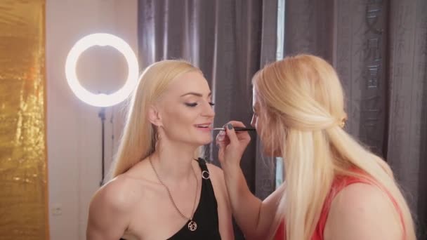 Make-up-Artist mit Pinsel zum Auftragen Lippenstift auf den Lippen schöne Frau. Nahaufnahme Anwendung Lipgloss auf Lippen Mode-Modell. Visagist macht Make-up Lippen. Schönheitskonzept. — Stockvideo