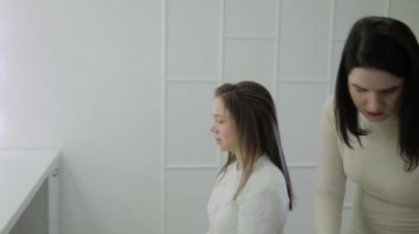 Genç bir kadın bir Kuaför koltukta oturur: Kuaför saç şekillendirme yapar. Genç sarışın kadın şık bir saç modeli yapmak için güzellik salonuna geldi.