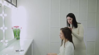 Genç bir kadın bir Kuaför koltukta oturur: Kuaför saç şekillendirme yapar. Genç sarışın kadın şık bir saç modeli yapmak için güzellik salonuna geldi.