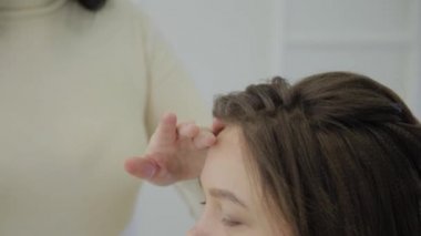 Genç bir kadın bir Kuaför koltukta oturur: Kuaför saç şekillendirme yapar. Genç sarışın kadın şık bir saç modeli yapmak için güzellik salonuna geldi.