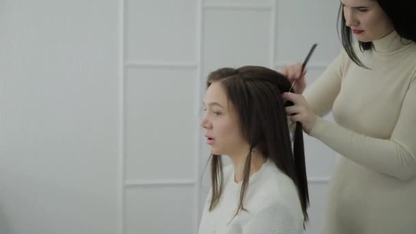 Mladá žena sedí v křesle kadeřníci: kadeřník dělá vlasový styling. Mladá světlovlasá žena přišla do salonu krásy vytvořit stylový účes. — Stock video