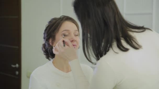 Professional makeup artist makes makeup a very beautiful woman. — Stock Video