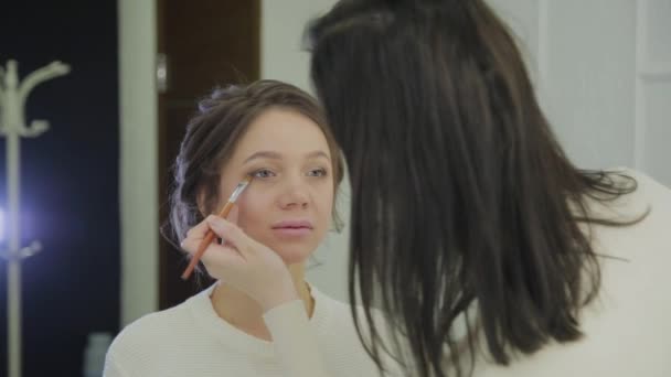 Artista de maquillaje profesional hace que el maquillaje una mujer muy hermosa . — Vídeo de stock