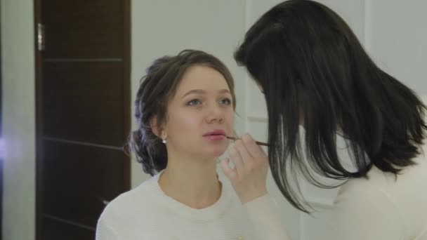 Maquilleur utilisant le pinceau pour l'application rouge à lèvres sur les lèvres belle femme. Fermer application brillant à lèvres sur les lèvres modèle de mode. Visagiste qui se maquille les lèvres. Concept de beauté . — Video