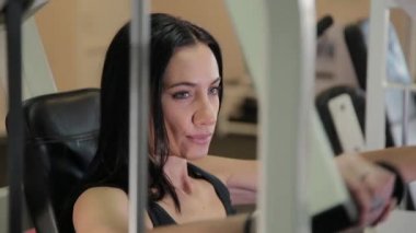 Güzel sportif esmer kadın bir simülatör göğüs ve kol kasları için devreye girer. Yaşam tarzı kavramı.