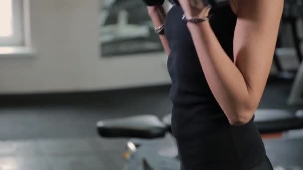 Szép sportos fiatal lány vonatok súlyzók bicepsz az edzőteremben. — Stock videók