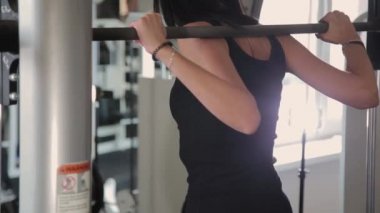 Spor salonunda omuzlarında güzel atletik genç kız crouches.