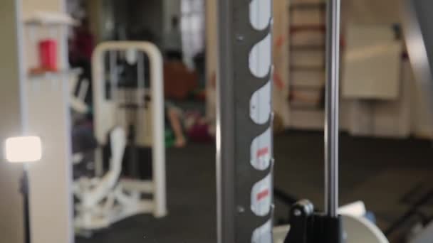 Belle sportive jeune fille s'accroupit sur les épaules dans la salle de gym . — Video