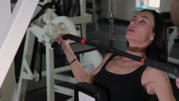 Güzel atletik genç kız göğüs simülatör spor salonunda bir çekme gerçekleştirir. — Stok video