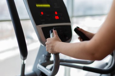 Atletik kız spor salonu yan görünümünde bir elipsoid yapıyor. Kadın trende bir elipsoid. Spor ve sağlıklı yaşam konsepti.