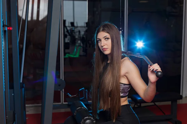 Mycket vacker flicka tränar rygg på gymmet på gymmet. — Stockfoto