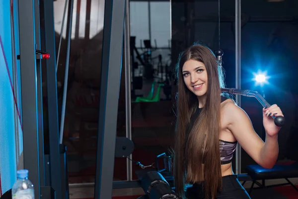 Mycket vacker flicka tränar rygg på gymmet på gymmet. — Stockfoto