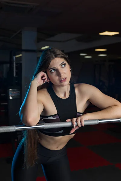 Beautiful sexy fitness model emotionally posing at the athletic barbell in the gym. — Stock Photo, Image