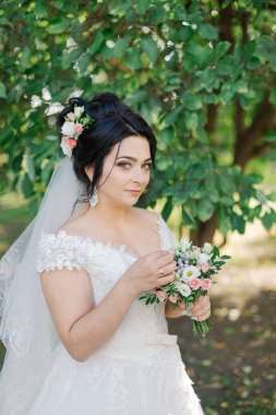 Çok güzel bir gelin buketi tutuyor.