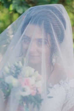 Çok güzel bir gelin buketi tutuyor.