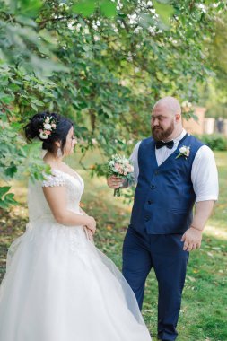 Onların düğün günü üzerinde yeni evliler park, birbirine, gülümseyen bakarak yürüyor.