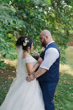 Onların düğün günü üzerinde yeni evliler park, birbirine, gülümseyen bakarak yürüyor.