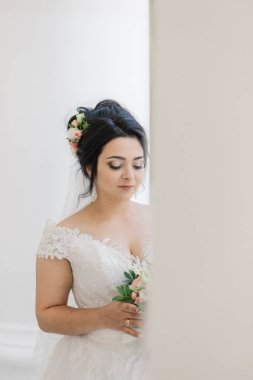 Çok güzel bir gelin buketi tutuyor.