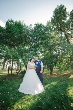 Onların düğün günü üzerinde yeni evliler park, birbirine, gülümseyen bakarak yürüyor.