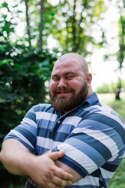 Parkta şişman adam içine belgili tanımlık çerçevelemek, aşırı kilo olan bir adam portresi görünüyor.