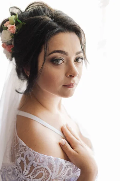 Foto de moda de la novia hermosa con el pelo oscuro en vestido de novia elegante y diadema posando en la habitación en la mañana de la boda. —  Fotos de Stock