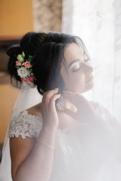 时尚图片：美丽的新娘，深色头发，穿着雅致的婚纱，头戴皇冠，早上在房间里摆姿势. — 图库照片