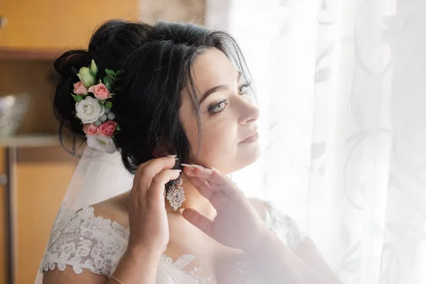 Foto de moda de la novia hermosa con el pelo oscuro en vestido de novia elegante y diadema posando en la habitación en la mañana de la boda. —  Fotos de Stock