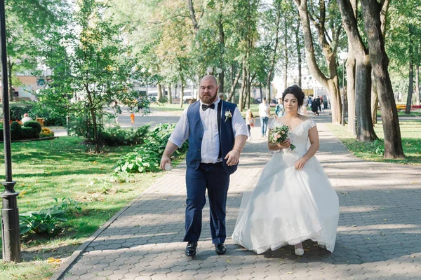 Os recém-casados estão andando no parque e sorrindo um para o outro . — Fotografia de Stock