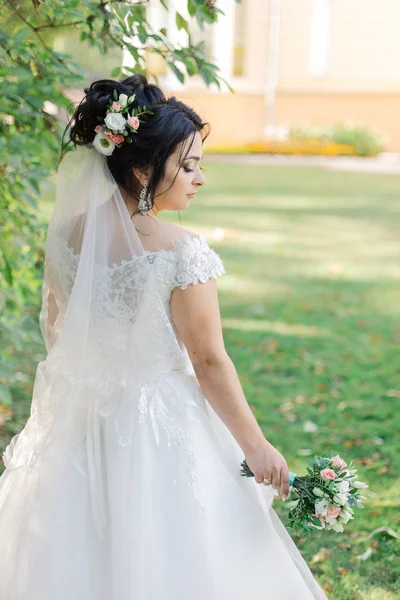 Mooie bruid in een prachtige jurk en boeket. — Stockfoto