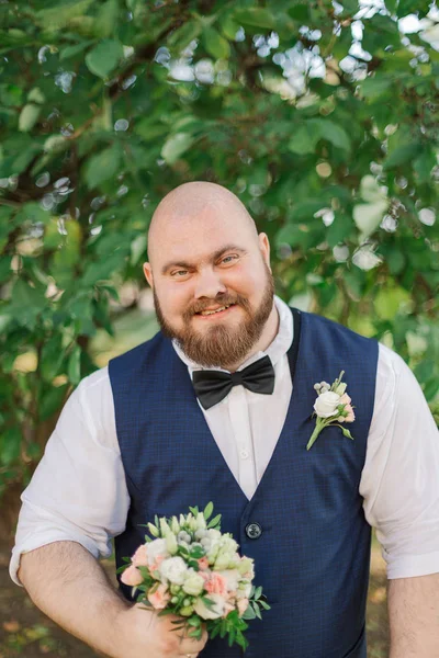 Elegante novio gordo barbudo con ramo de bodas en el parque . — Foto de Stock