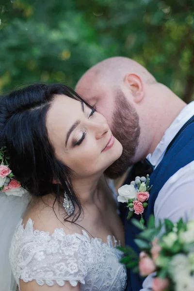 Recién casados en el día de su boda están caminando en el parque, mirándose, sonriendo . — Foto de Stock